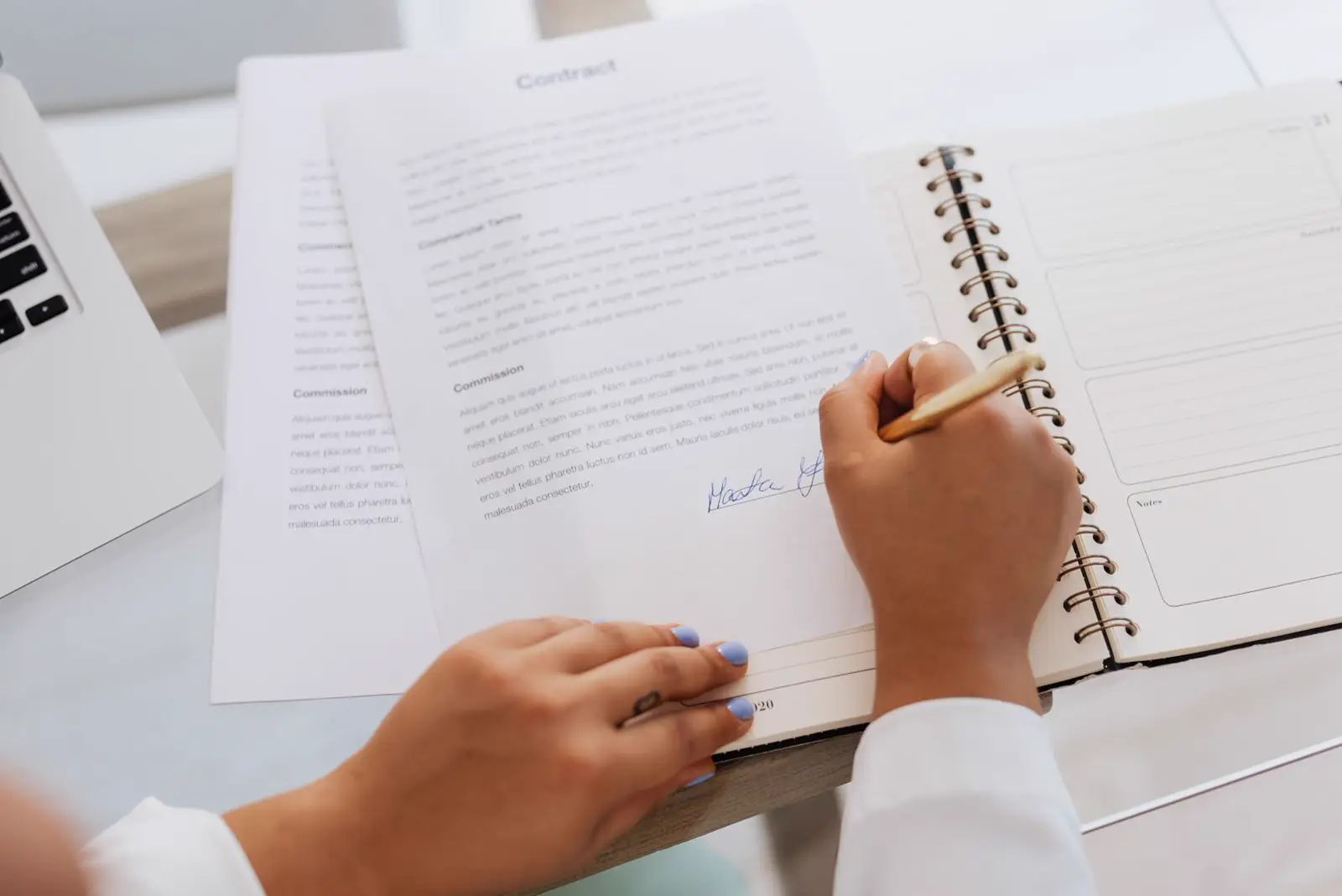 A signer filling in a contract on a notebook next to the printed pages